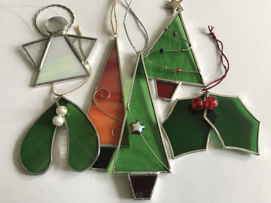 A selection of stained glass Christmas decorations including trees, mistletoe and holly